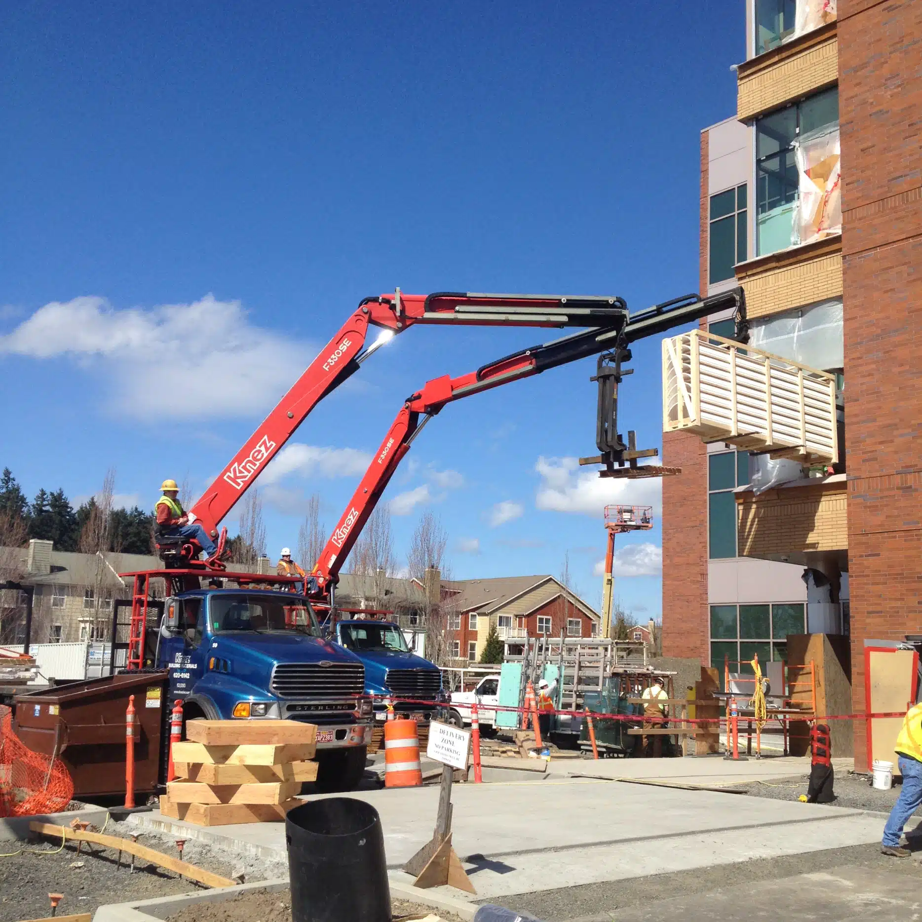 2 Knez boom trucks in action at a job site